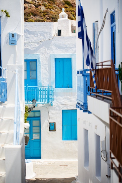 Beautiful street in old traditional Greek cycladic village of Plaka with white houses and colorful d...